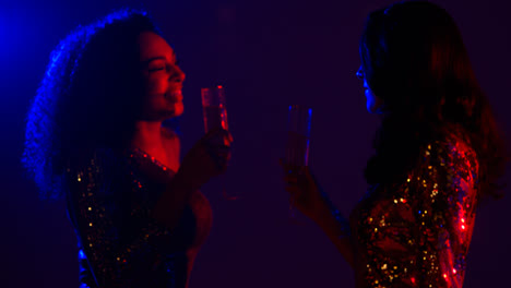 Close-Up-Of-Two-Women-In-Nightclub-Or-Bar-Celebrating-Doing-Cheers-And-Drinking-Alcohol-1